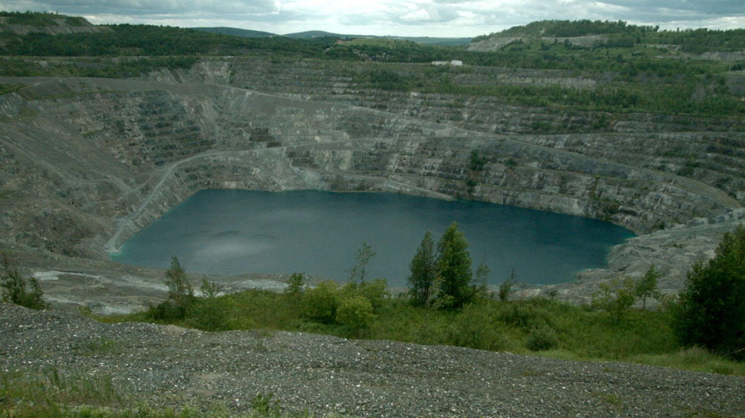 an old opencut asbestos quarry lake filled with water, a still image the film Asbestos 2016