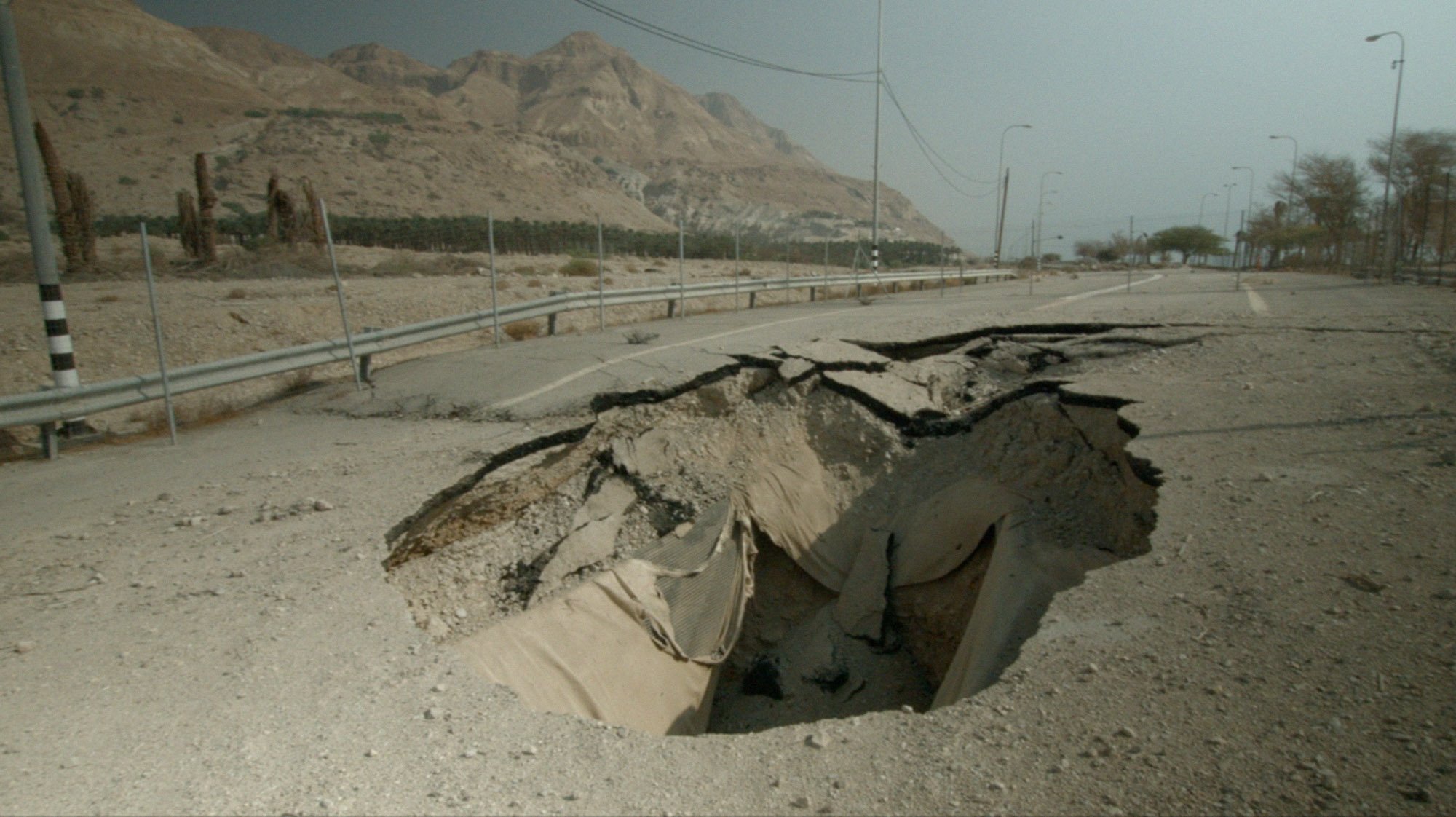 a sinkhole in a road, a still image from the film Salarium